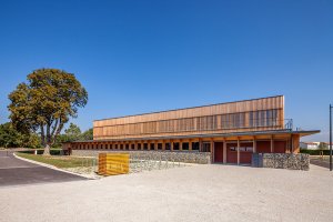 R2k architecte: tělocvična ve francouzském Crestu (2012); dřevěná rámová konstrukce s výplní ze slaměných balíků