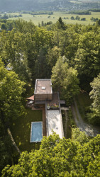 Stavba stojí na protáhlém pozemku mezi stromy. (Dům v Davli, 0,5 Studio)