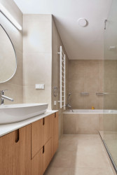 Pro koupelnu zvolili autoři jemné béžové terazzo. Ložnice navazuje na materiály zvolené pro obývací část - dubové dřevo v kombinaci se šedobéžovou. (Rekonstrukce bytu ve Strašnicích, MENU architekti)