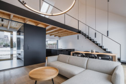 Uvnitř domu. Nad obývacím pokojem je ochoz. (Přízemní dům s fasádou z opalovaného dřeva; Luni architekti)