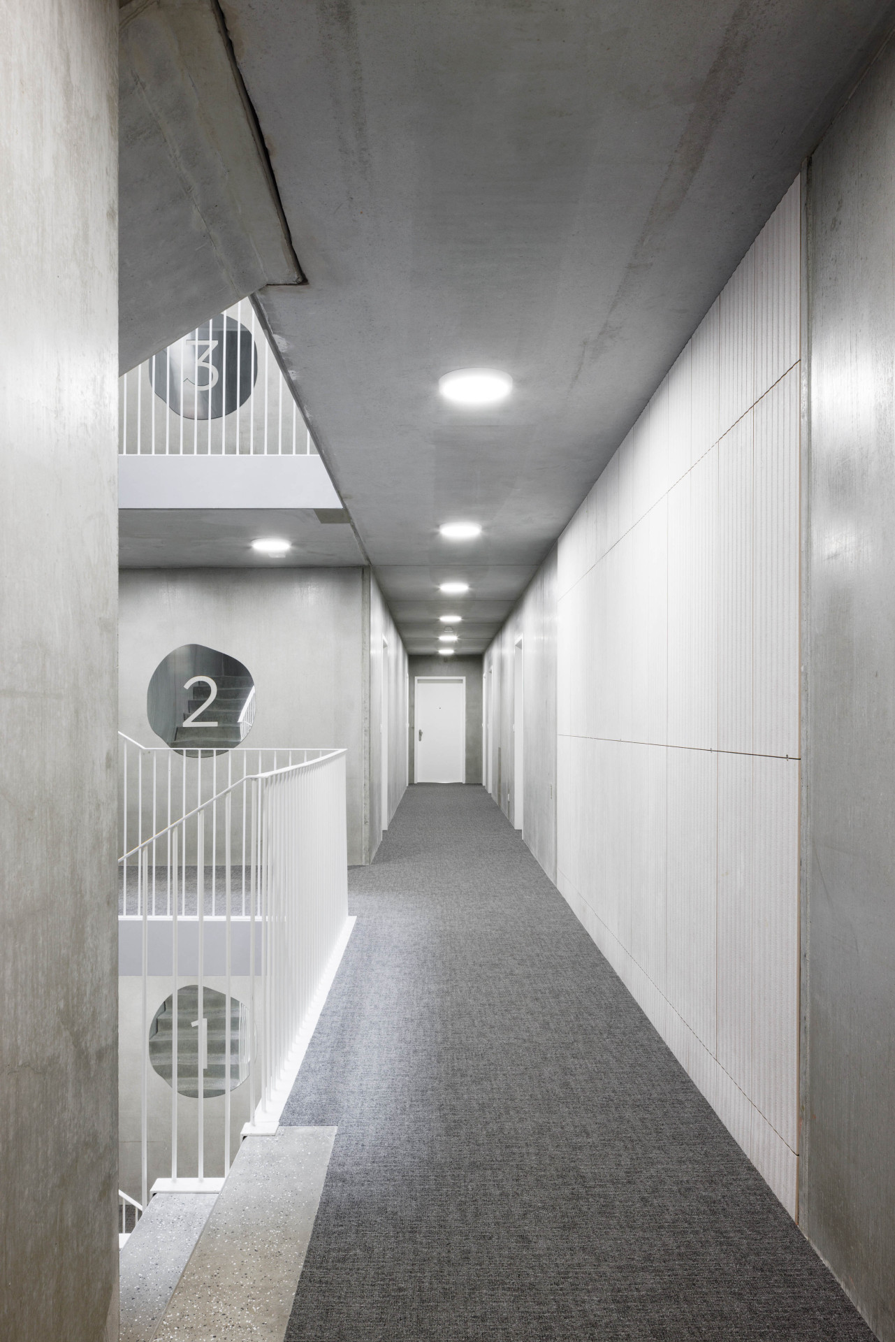 Dalším bonusem pro obyvatele jsou elegantní společné prostory, kde kontrastuje obnažená konstrukce s měkkým koberecem a zrcadly na stěnách.