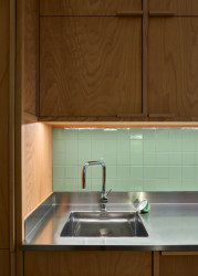 Kuchyňská linka je zhotovena z nerezového plechu, který se objevuje i na nábytku v koupelně či předsíni. (Rekonstrukce bytu ve Vršovicích, Amulet architekti)
