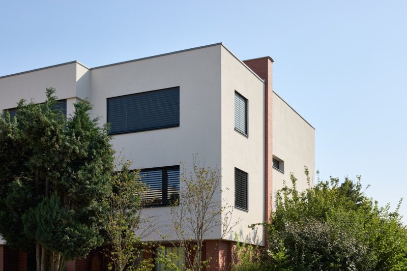Změnil se také tvar okenních otvorů a zmizely úzké balkony. (Řadový dům v Čimicích, Plus One Architects)