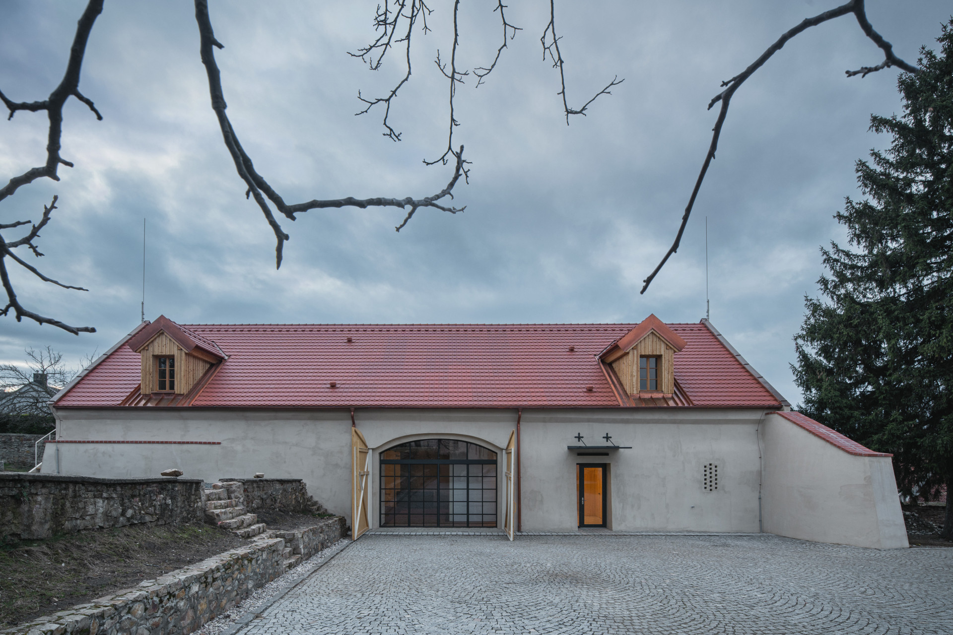 Bývalá farní stodola, za vraty je dnes skleněný portál. (Komunitní centrum v bývalé stodole, studio Raketoplán)