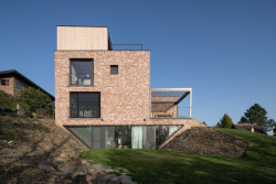 Část domu je zapuštěná pod terénem. Podzemní místnosti mají prosklenou stěnu do spodní části zahrady. (Dům v Olešku, AbtSmolen)