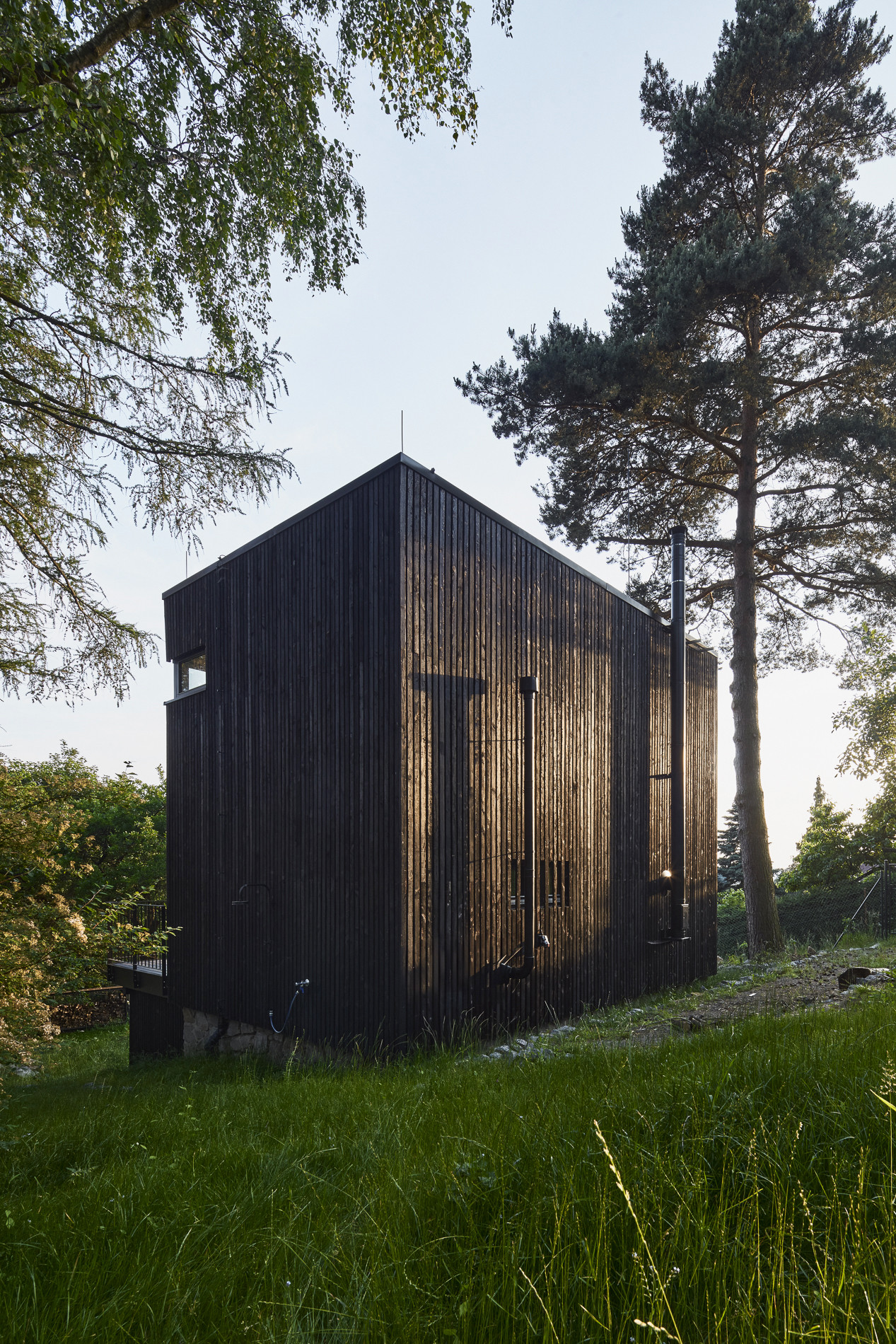 Chata Kostka na Vysočině, 0, 5 Studio: Díky laťování z opáleného dřeva se povrch domu mění pod úhlem dopadajícího světla a jeho členitost může evokovat kůru stromů z okolí místa, kde dům stojí