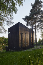 Chata Kostka na Vysočině, 0, 5 Studio: Díky laťování z opáleného dřeva se povrch domu mění pod úhlem dopadajícího světla a jeho členitost může evokovat kůru stromů z okolí místa, kde dům stojí