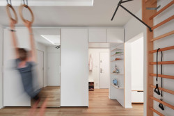 Původní dispozice obsahovaly nepraktickou klikatou chodbu. Nyní je místo ní místnost společná všem - prochází se ní do soukromých pokojů a koupelen, slouží ale také jako herna a tělocvična. (Panelákový byt na Jarově, Kateřina Hodková a Markéta Smrčková)