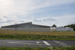 Pohled na nový hangár z dálky, za ním jedna ze starších staveb v areálu. (Hangár ve Zbraslavicích, Studio Raketoplán)