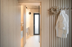 „Výrazným motivem interiéru jsou lamely hned v několika formách. Slouží jednak jako protiváha hladkým plochám nábytku – zlepšují akustiku interiéru – a dále pomáhají členit jednotlivé zóny prostoru." říká Kateřina Horych. (Interiér rodinného domu v Popůvkách, Atel!er)