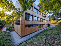 Škola v Českobrodské ulici od  ECOTEN: Pro povrchovou úpravu ENVILOP autoři rekonstrukce zvolili vláknocementové fasádní desky Swisspearl Patina Original (dříve Cembrit) a dřevěný obklad, konkrétně rombusové tyče ze sibiřského modřínu bez povrchové úpravy