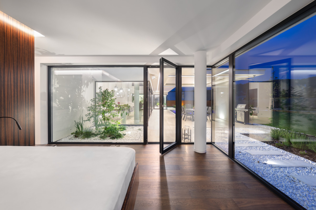Z ložnice je přes atrium vidět do obývacího pokoje a přes druhé atrium až do relaxační místnosti s vířivkou.  (Villa Všemina; Kareš Arch)