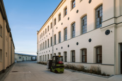 Továrna po rekonstrukci. Na fasádě jsou zachované reliéfy s květem lnu. (Rekonstrukce přádelny v Kežmarku; BEEF Architekti)