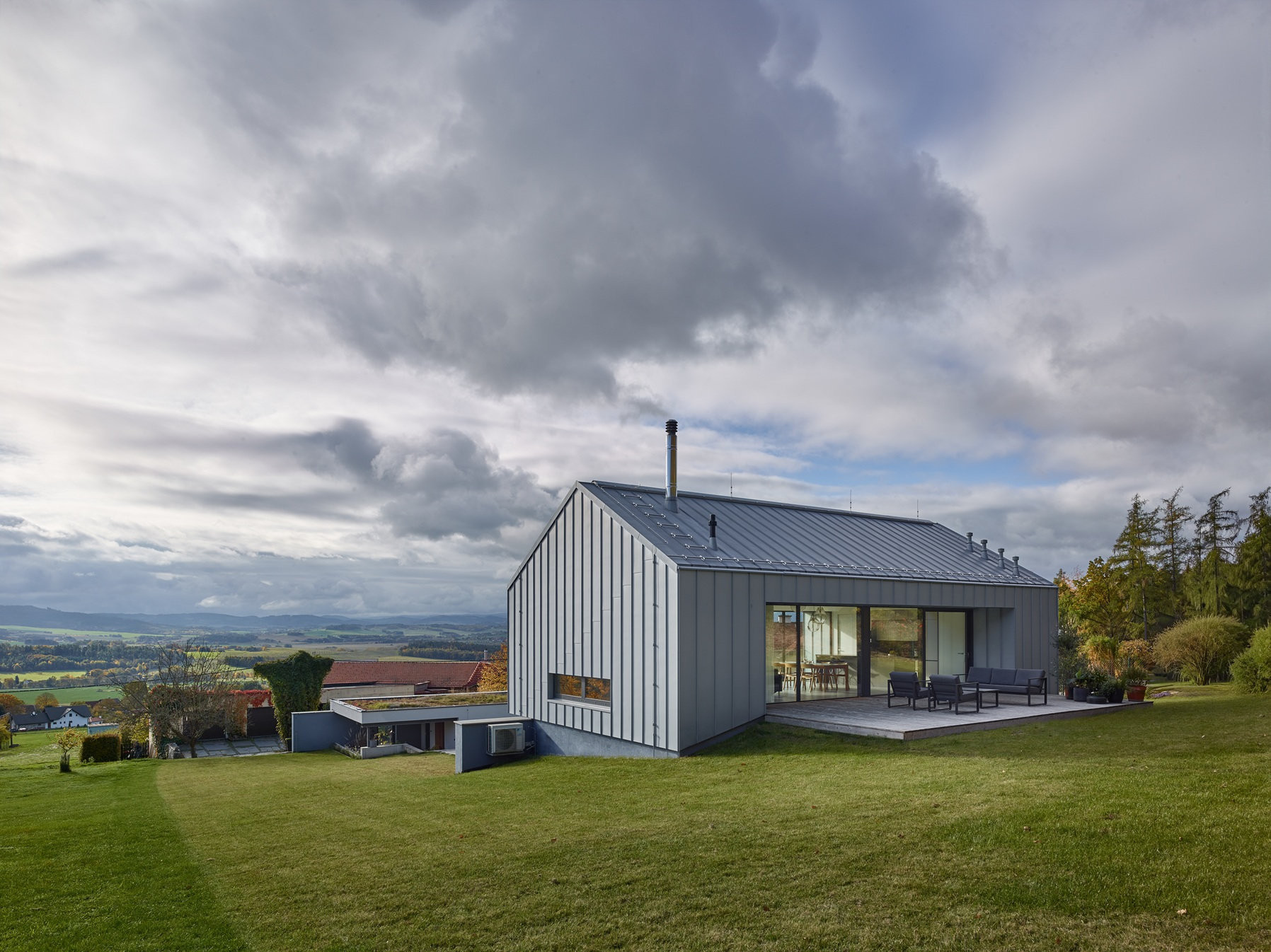 Při pohledu na dům z horní části pozemku se odhaluje jen komorní hmota se sedlovou střechou. (Rodinný dům u Klatov; Stempel Tesař architekti )