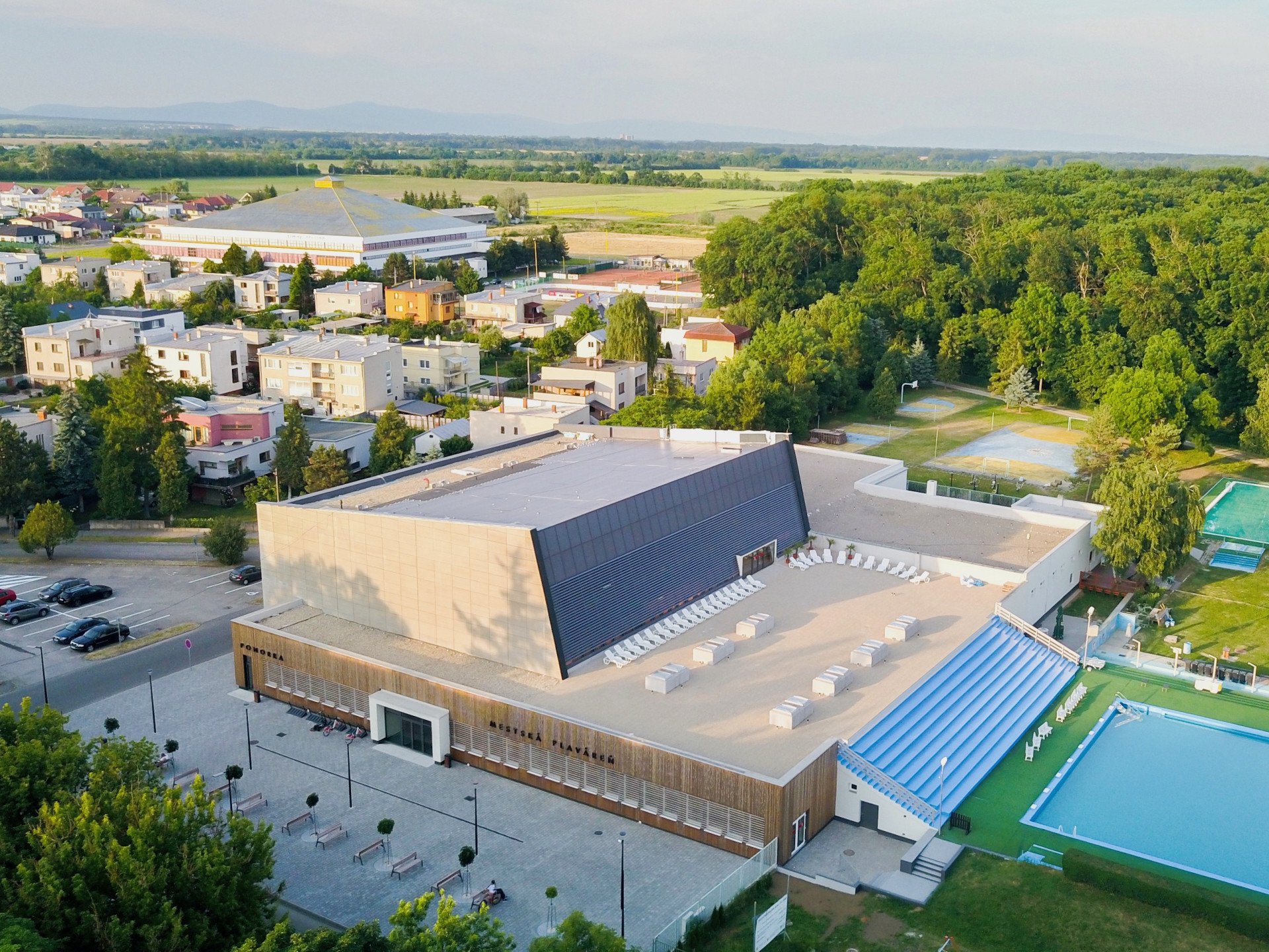 Bazén se nachází na předělu města a přírody a přiléhá k němu ještě venkovní koupaliště