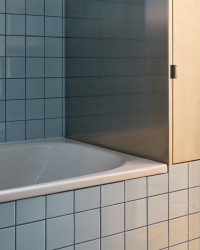 Pro nábytek v koupelně architekt zvolil povrchovou úpravu z nerezového plechu. (Rekonstrukce bytu ve Vršovicích, Amulet architekti)