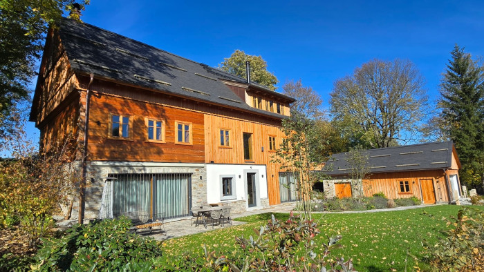 Rozsáhlá prosklená plocha a velká okna v roubence opticky rozšiřují interiér a navozují pocit volnosti.