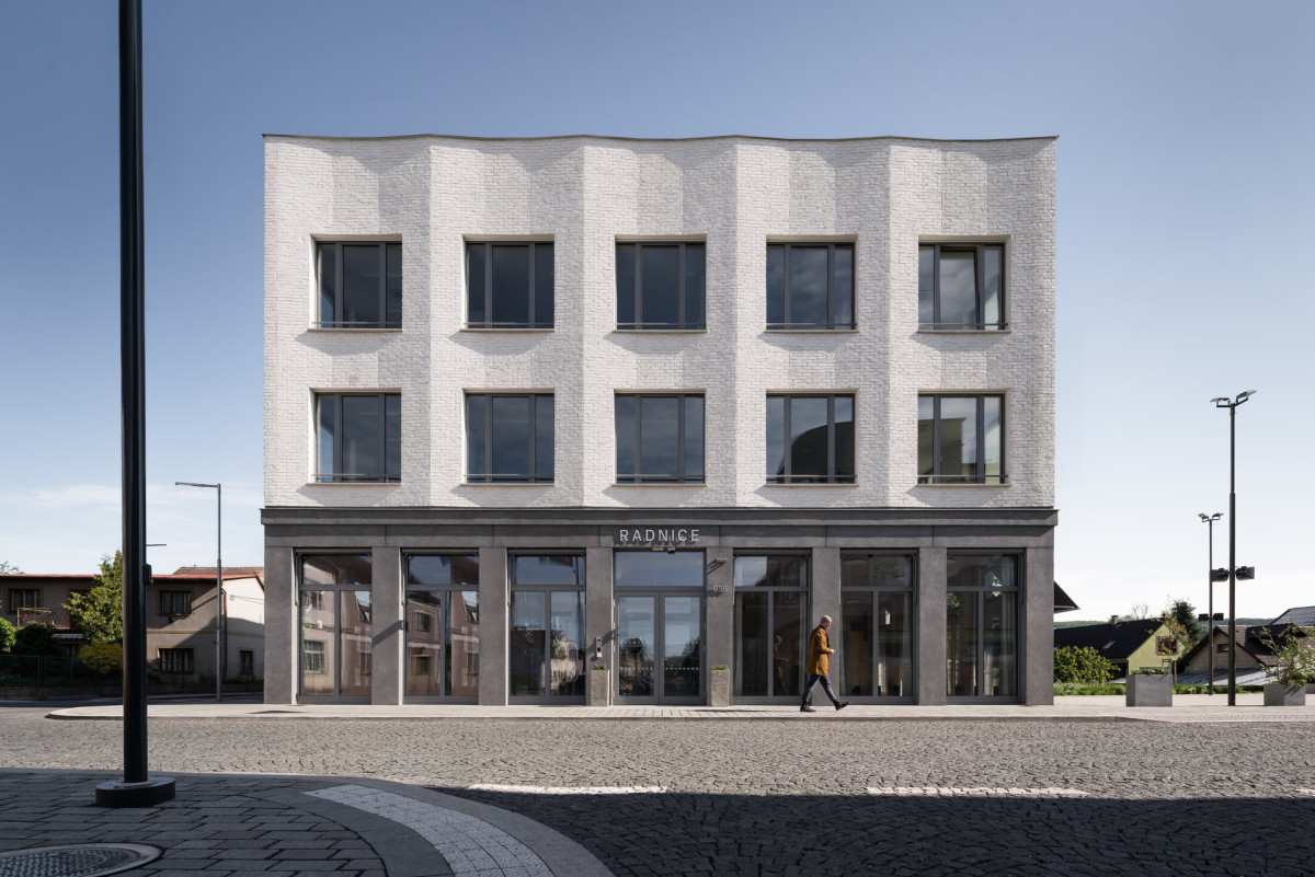 Detail vztahu budovy k náměstí - objekt působí jako přirozený organizující prvek veřejného prostoru. (Nová radnice s plastickou fasádou; re:architekti)
