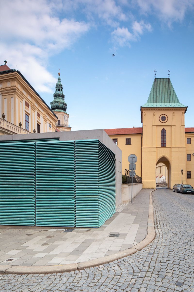 Lamely mají zelenkavou patinu, ladí tak s měděnými střechami historických staveb. (Vstupní objekt do zámeckých sklepů s trafostanicí v Kroměříži od Atelier Štěpán)