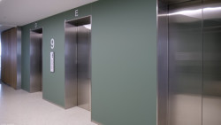 Výtahové šachty jsou obložené skleněným obkladem z matovaného skla - na fotografii Matelac Green Sage.
