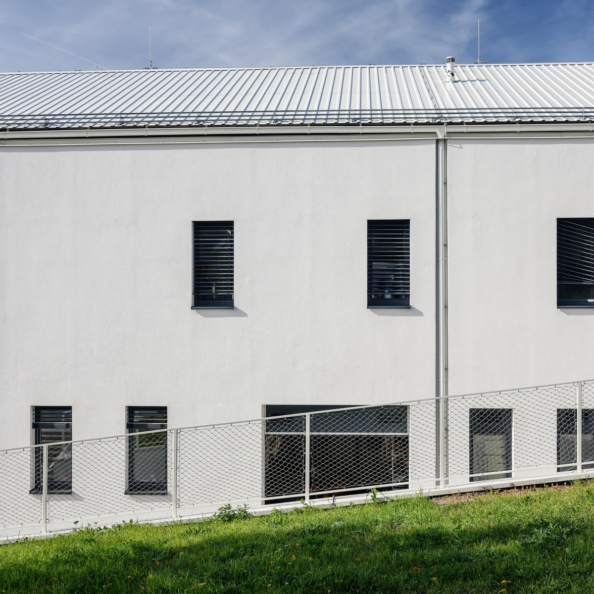 Parcela je svažitá, čehož architekti využili k zapuštění části komplexu do terénu. (Dětská léčebna se speleoterapií v Ostrově u Macochy; Adam Rujbr Architects)