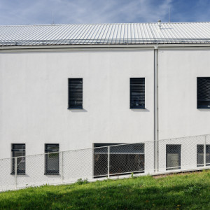 Parcela je svažitá, čehož architekti využili k zapuštění části komplexu do terénu. (Dětská léčebna se speleoterapií v Ostrově u Macochy; Adam Rujbr Architects)