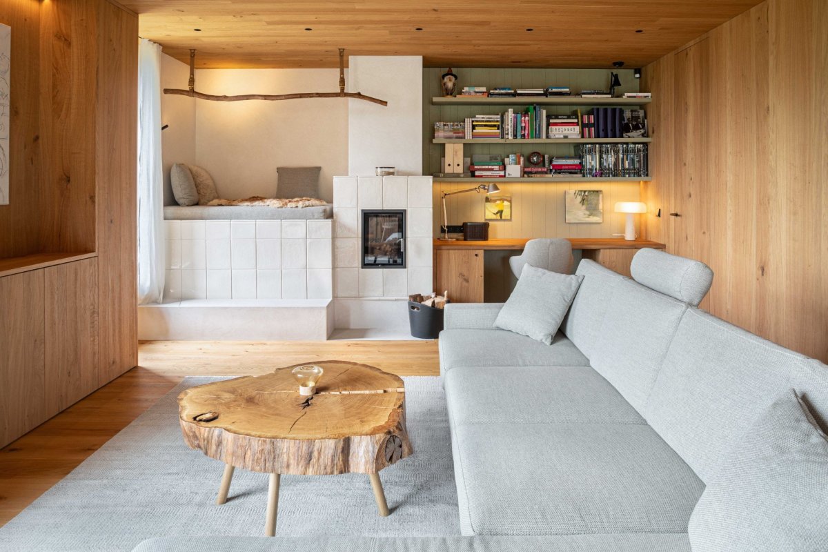 Kamna s ručně vyráběným kachlovým obkladem dodávají současnému interiéru útulný charakter horské chalupy. (OK PLAN ARCHITECTS, Rodinná bouda)