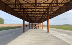 Čtvrtá strana je otevřená a chráněná plechovou střechou, pod kterou je umístěn dlouhý dřevěný stůl s dvěma lavicemi. (Zahrada Hage, Brendeland & Kristoffersen)