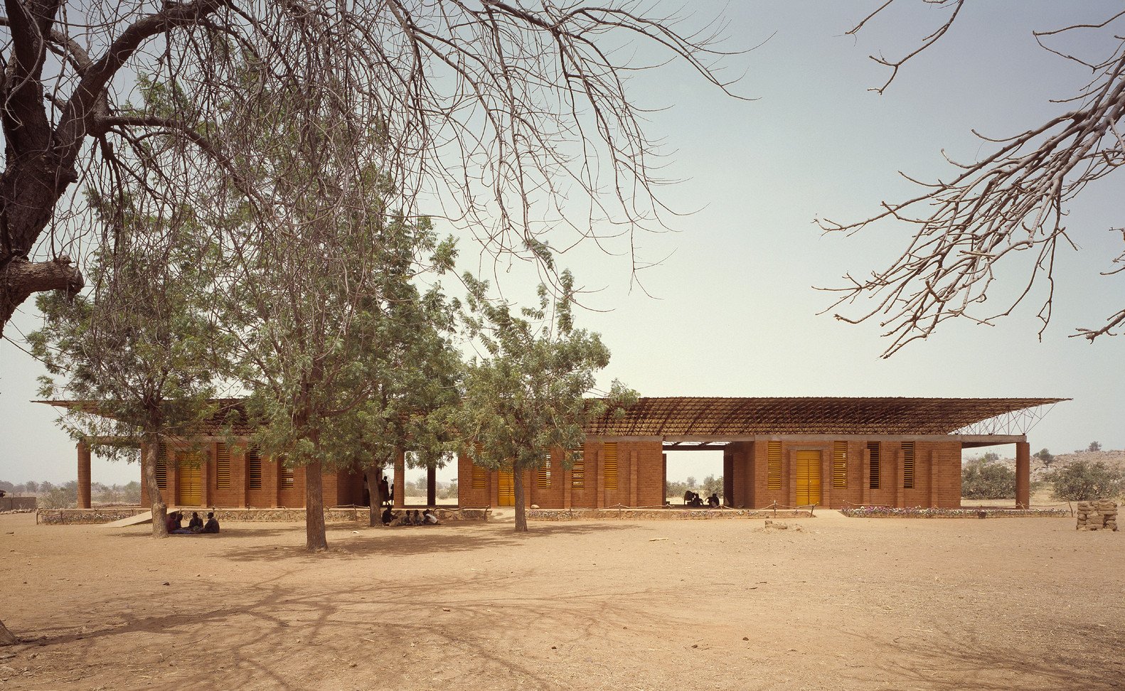 Diébédo Francis Kéré, rodák z Burkiny Faso, vystudoval architekturu na Technische Universität v Berlíně. Dnes v tomto městě sídlí i jeho ateliér Kéré Architecture. Svou tvorbu však zasvětil převážně prostředí, z nějž pochází. Vůbec první stavbu realizoval roku 2001 ve své rodné vesnici Gando. Jedná se o základní školu, za níž si odnesl cenu Aga Khan Award for Architecture 2004 – ta dlouhodobě sleduje převážně inovativní počiny v oblasti sociální architektury.
