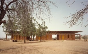 Diébédo Francis Kéré, rodák z Burkiny Faso, vystudoval architekturu na Technische Universität v Berlíně. Dnes v tomto městě sídlí i jeho ateliér Kéré Architecture. Svou tvorbu však zasvětil převážně prostředí, z nějž pochází. Vůbec první stavbu realizoval roku 2001 ve své rodné vesnici Gando. Jedná se o základní školu, za níž si odnesl cenu Aga Khan Award for Architecture 2004 – ta dlouhodobě sleduje převážně inovativní počiny v oblasti sociální architektury.