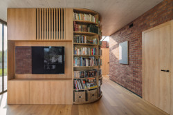 Pilíř s televizí a atypickou knihovnou, nestojí u stěny ale uprostřed místnosti (Cihlový dům v Pardubicích; architekti Jakub Dvořák a Michal Bílek)