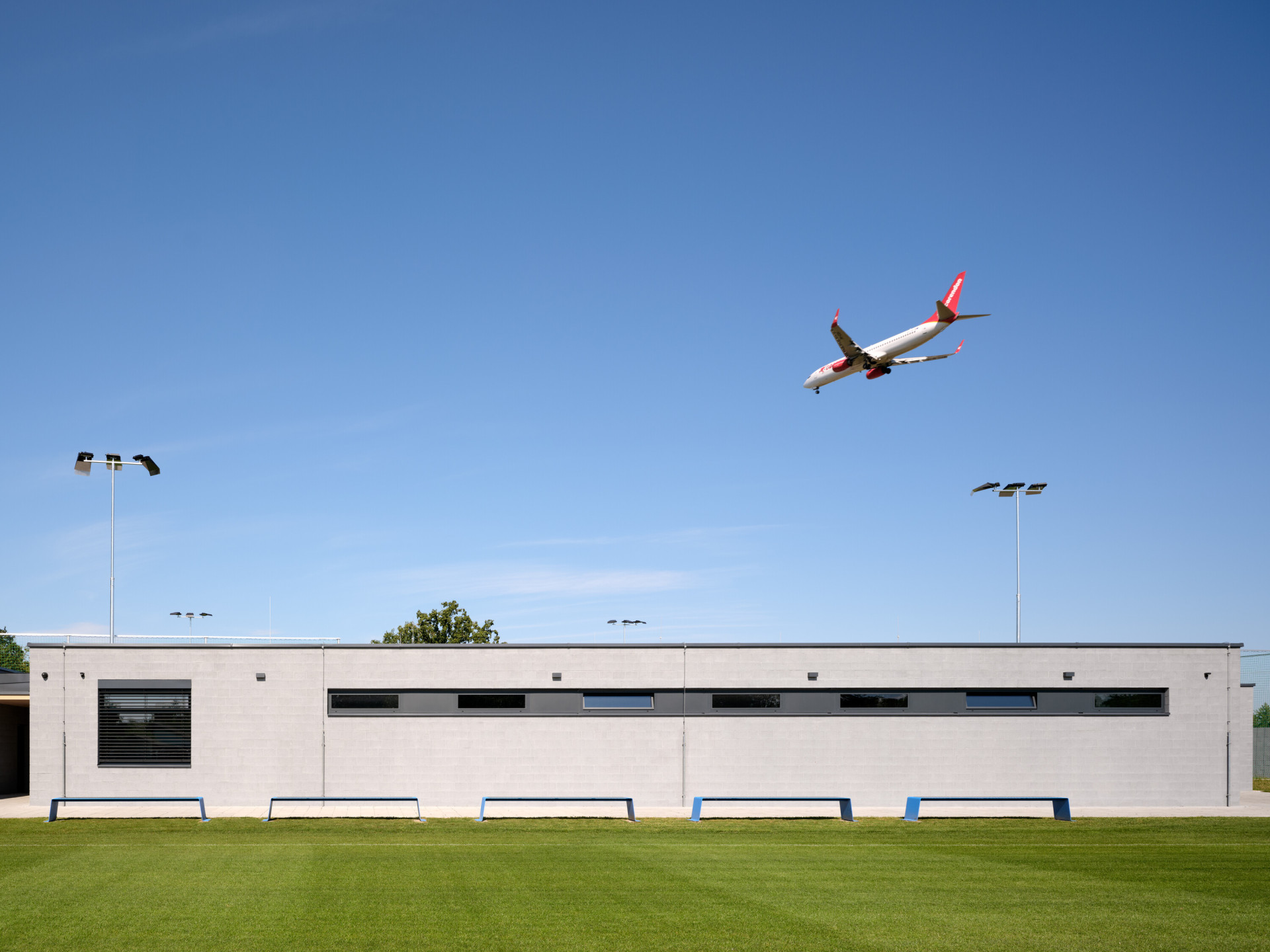 Divácká tribuna je krytá vykonzolovanou dřevěnou střechou, pod kterou je také kabina hlasatele s dobrým výhledem na celé fotbalové hřiště. (Sportovní areál SK Planá, PROAM ARCHITEKTI)