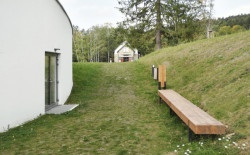 Za novým návštěvnickým centrem osady Ploština stojí studio Art Consultancy.