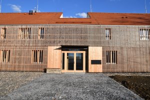 Komunitní dům pro seniory v Holasovicích, City Upgrade: Komunitní centrum pro seniory stojí ve středu ani ne dvoutisícových Holasovic, je novostavbou, ačkoliv původně mělo být vestavbou do starší stodoly