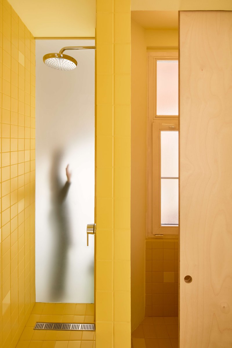 Přirozené světlo do koupelny propouští dva světlíky – jeden tvoří přímo čelní stěnu sprchy. (Byt pro malířku v Praze-Holešovicích od Plus One Architects)