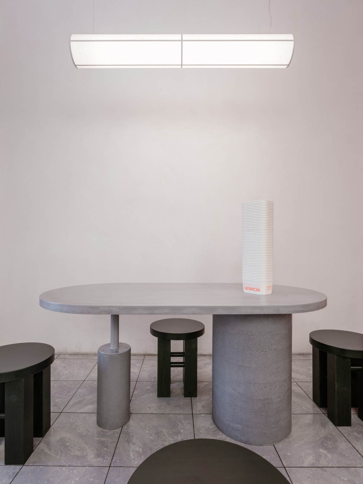 Výrazným prvkem interiéru je společný betonový stůl určený pro sdílené stolování. (The Kimchi; SOA architekti)