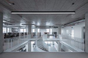 Městská knihovna v Praze na Petřinách, studio MONOM: Racionální charakter budovy podtrhují odhalené instalace na stropě.