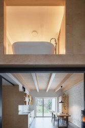 Rodinný dům s přístavbou v Plzni, PRO-STORY: A pak taky obklad stěny koupelny, která visí v převýšeném prostoru nad obývacím pokojem.