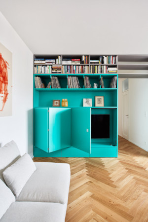 Výrazným elementem interiéru je tyrkysová vestavěná skříň se skrytou televizí. (Flexibilní rekonstrukce pražského bytu; Markéta Bromová architekti)