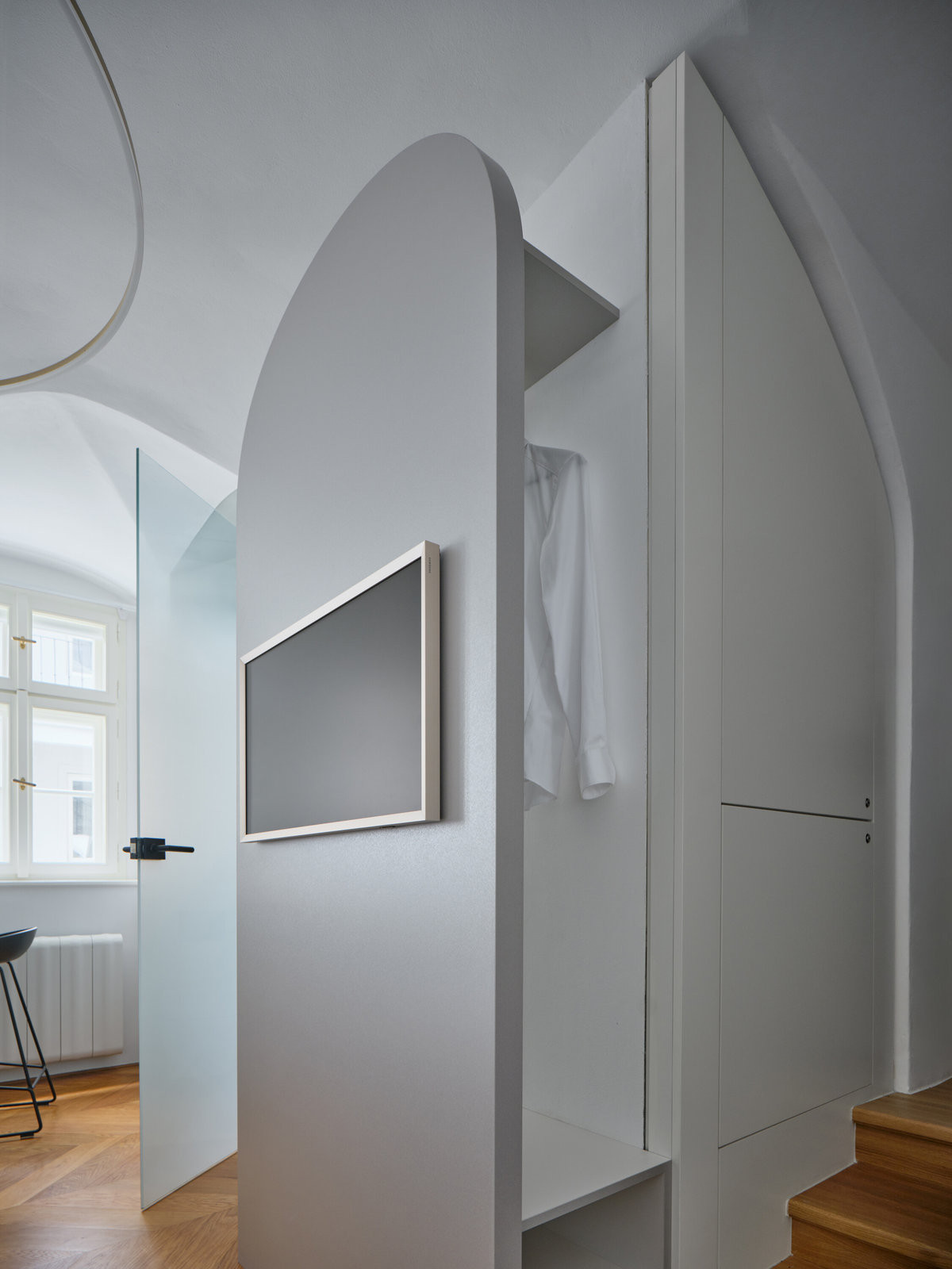 Televizní stěna, za níž jsou úložné prostory a skryté technologie. (Rekonstrukce miniapartmánu; ateliér Tunicate)