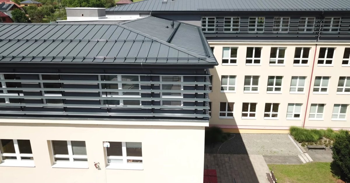 Nástavba základní školy Vidče vyřešila nedostatek prostor pro výuku. Pracuje s kontrastem mezi tmavou současnou vrstvou a původní světlou fasádou z 80. let.