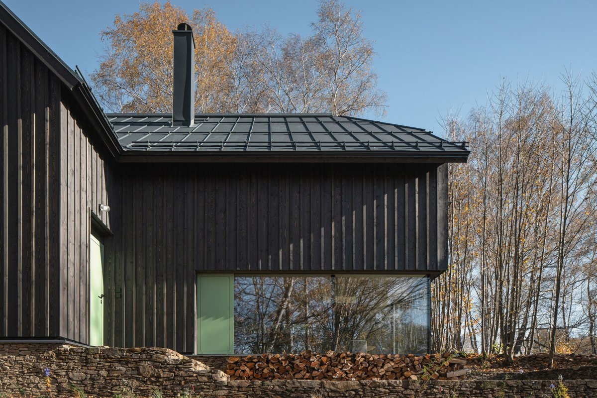 „V okolí časté zelené okenice byly inspirací pro větrací otvírky doplňující bezrámové zasklení oken,“ dodávají k barevnému řešení ještě architektky. (Chata na Šumavě, ateliér Markéty Cajthamlové)