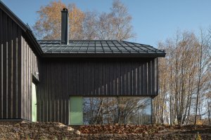 „V okolí časté zelené okenice byly inspirací pro větrací otvírky doplňující bezrámové zasklení oken,“ dodávají k barevnému řešení ještě architektky. (Chata na Šumavě, ateliér Markéty Cajthamlové)