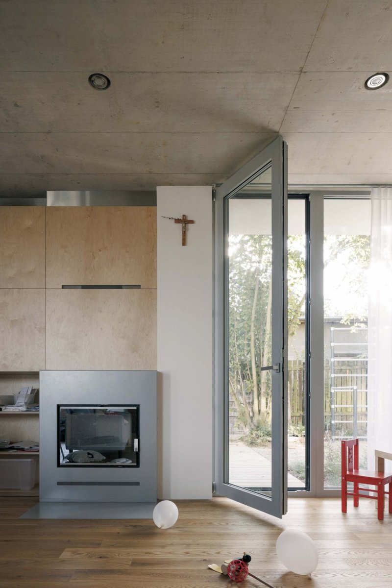 Do hlavního obytného prostoru ústí kuchyň, knihovna, krb a oddělitelné schodiště. (Rodinný dům v Radotíně, Papundekl architekti)