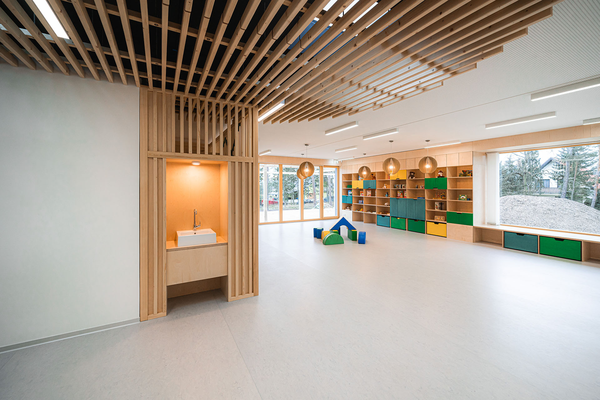 Interiér je měkký, organický, dřevěný. (Mateřská škola ve Vědomicích, Architip)