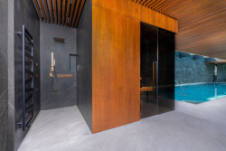 Designová finská sauna TAO v privátním spa disponuje tmavým obkladem, černými doplňky, stěnami zasklenými zatmaveným sklem a zádovým infrapanelem. 
