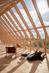 Víkendový dům "Das Glashaus" v Německu, Sigurd Larsen: Druhé podlaží domu nabízí odpočinek přímo pod dřevěným krovem. Skrze celoprosklenou západní část střechy lze vyhlížet okolní pole a lesy.