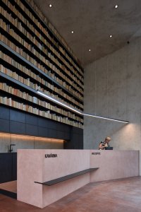 Obnova Červeného kostela, atelier-r: Nové moderní přístavbě dominuje recepce s menší kavárnou zhotovená z betonu v jemném růžovém odstínu