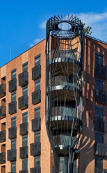 Nárožní dům "Flaška" - lodžie rohových bytů umístěné do kovové konstrukce láhve. (Transformace Lihovaru Smíchov; Black n´ Arch)