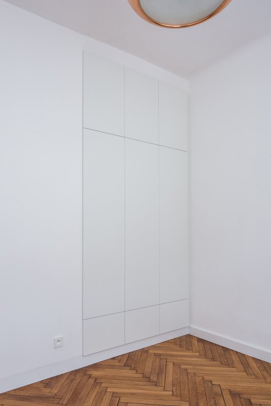 Vestavné skříně splývají s bílou omítkou stěn. Dvířka mají z lamina. (Rekonstrukce bytu v Praze, BY architects)